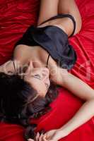 Tempting brunette lying on silk sheets