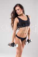Sexy woman posing while exercising with dumbbells