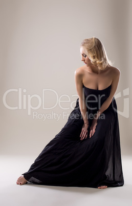 Attractive blonde in black dress posing at camera