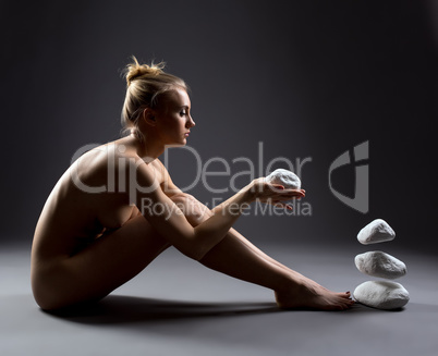 Focused nude girl makes stones to fly by thought