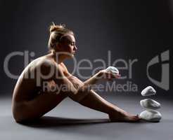 Focused nude girl makes stones to fly by thought