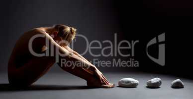Shot of nude female telekinetic posing with stones