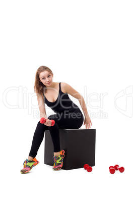 Lovely female athlete posing sitting on cube