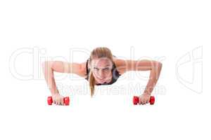 Smiling female athlete push-ups on dumbbells