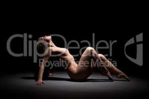 Seductive nude dancer posing lying in studio