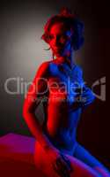 Beautiful naked model posing in red and blue light