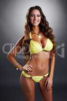 Happy tanned brunette posing in yellow swimsuit