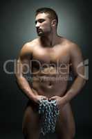 Naked muscular man posing with chain