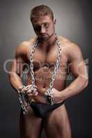 Muscled man posing wrapped himself with chain