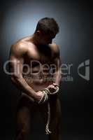 Concept of bodybuilding. Nude man with torn rope