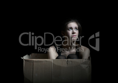 Upset girl posing sitting in cardboard box