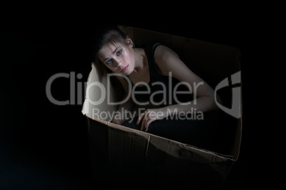 Image of sad young girl posing in cardboard box