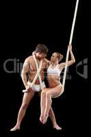 Strong male dancer hugging girl sitting on rope