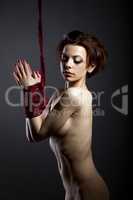Kinbaku concept. Naked girl posing with hands tied
