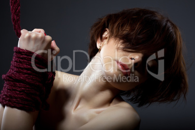 Kinbaku concept. Red-haired girl with tied hands