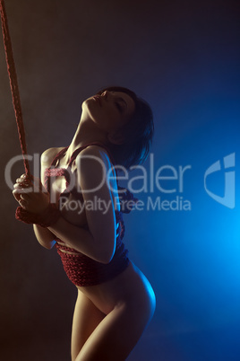 BDSM concept. Languid nude woman tied with rope