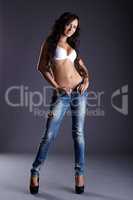 Tanned smiling model dressed in bra and jeans