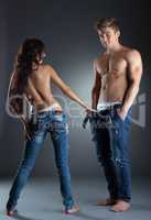 Playful topless girl pulls jeans of her boyfriend