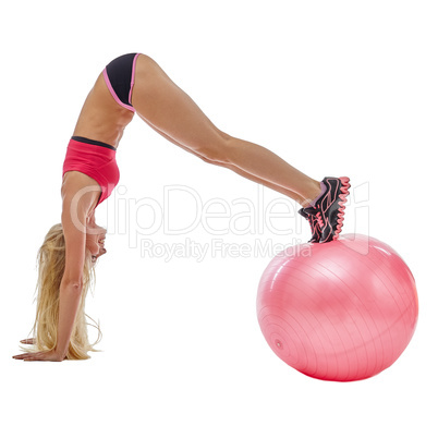 Energetic girl doing handstand on fitness ball
