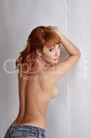 Rear view of sexual redhead model posing topless