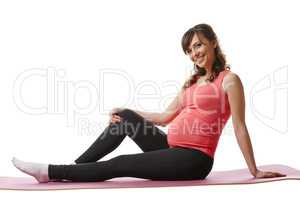 Joyful pregnant woman sitting on fitness mat