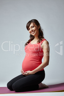 Sporty expectant mother smiling happily at camera