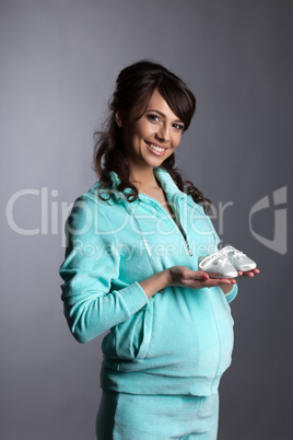 Charming expectant mother posing with baby shoes