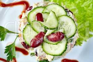 Delicious salad decorated with cucumber and beans