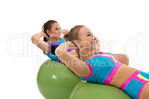 Smiling girls pump abdominals on fitness balls