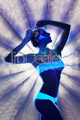 Unreal girl with luminous body art in spotlight