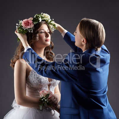 Lesbian wedding. Groom puts wreath on bride's head