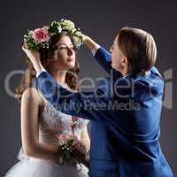 Lesbian wedding. Groom puts wreath on bride's head