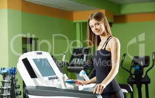 Cute girl exercising on simulator in gym