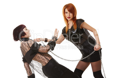 Redhead dominatrix keeps chained submissive girl