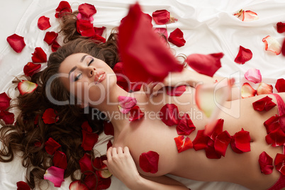 Image of seductive woman showered with rose petals