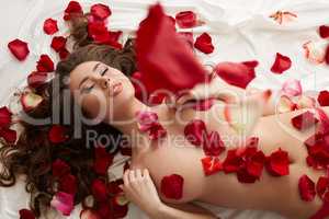 Image of seductive woman showered with rose petals