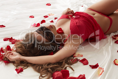 Curvy slim girl with blindfold posing in bed