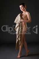 Nude woman posing with sackcloth in studio