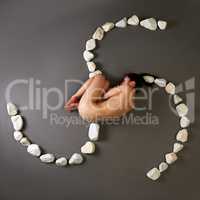 Top view of naked woman curled up with stones