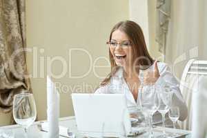 Laughing businesswoman showing thumbs up at lunch
