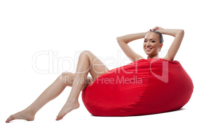 Laughing naked girl resting in comfortable pouf