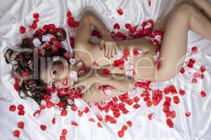 Tempting naked woman posing in rose petals