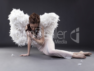 Fascinating girl in angel costume posing at camera