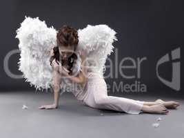 Fascinating girl in angel costume posing at camera