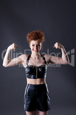 Smiling red-haired female dancer showing biceps