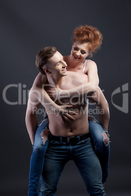 Happy young couple touts jeans. Studio photo