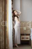 Harmonous woman in negligee standing at window