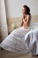 Half-naked thoughtful bride posing in hotel room