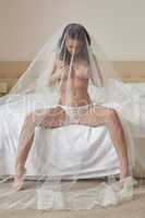 Sexy bride posing provocatively in hotel room