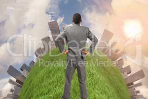 Composite image of businessman standing with hands on hips